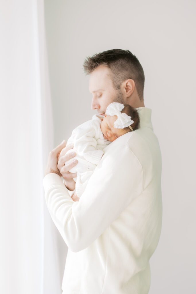 a dad embraces his baby girl during Newborn Photos in Edina, MN.