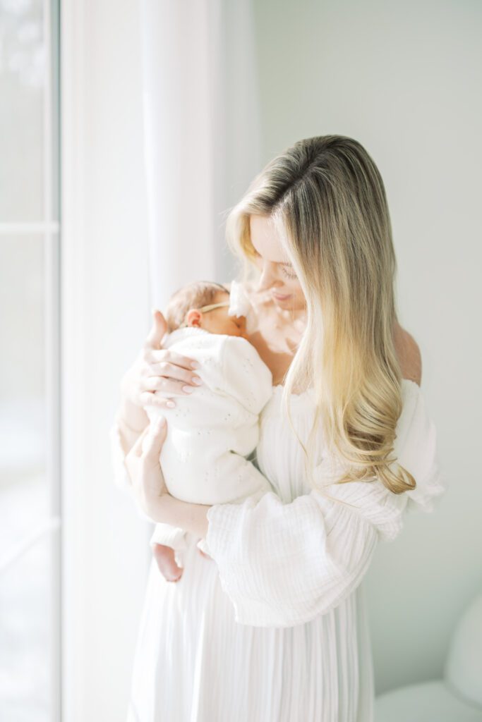 a mother holds her baby in a photography studio during her Edina Newborn Photos.