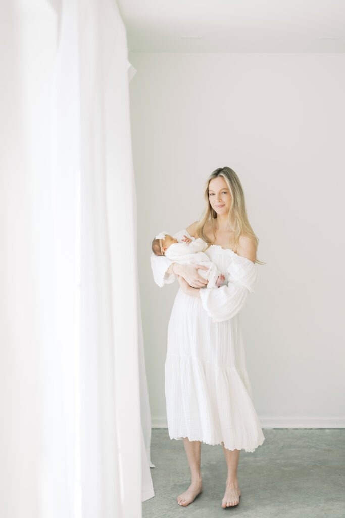 a mother holds her new baby in a white studio during their Newborn Photos in Edina, MN with Morgan Walworth Photography.