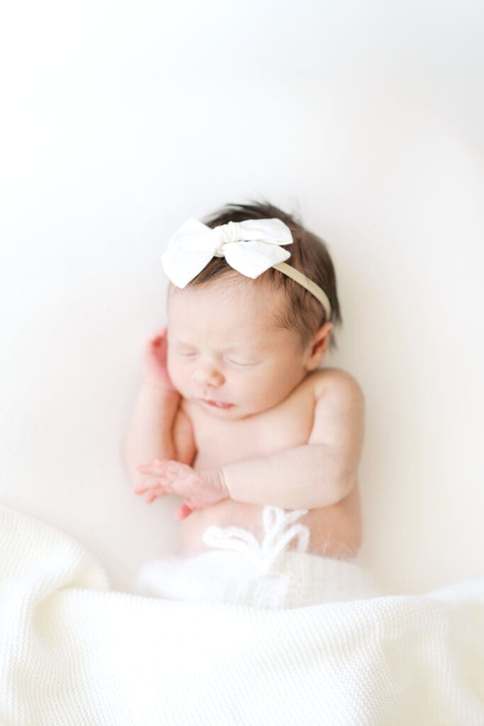 a baby girl sleeps on a white blanket during her newborn photos with Minneapolis Newborn Photographer, Morgan Walworth.