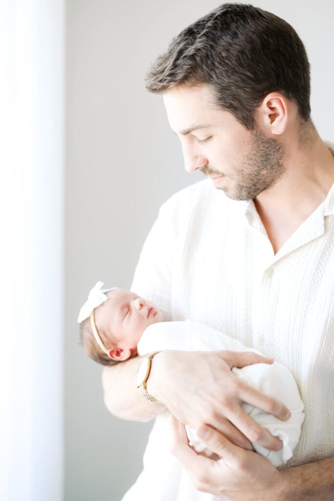 a new dad smiles down at his newborn daughter during Minneapolis Newborn Photos.