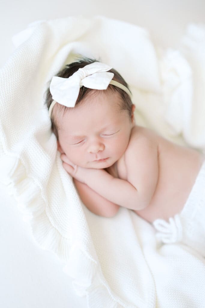 a baby girl sleeps on white sheets during her baby photos in Minneapolis.