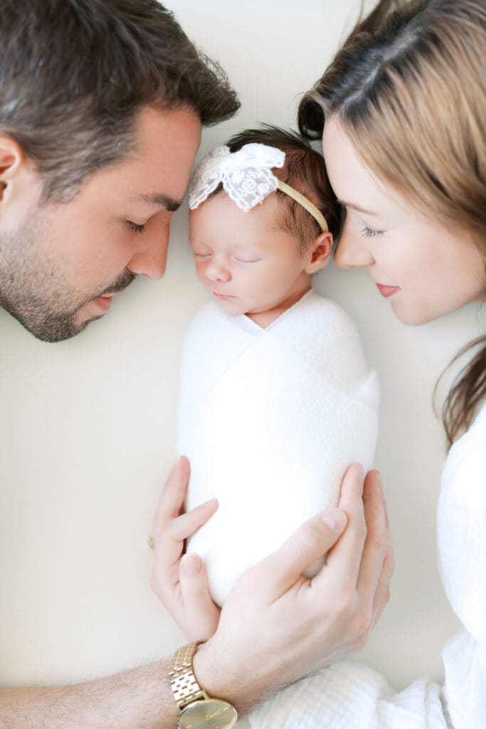 a mom and dad snuggle their newborn baby girl during Newborn Photos in Minneapolis, MN.